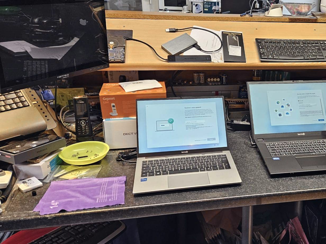Sur l’établi de l’atelier : un combiné sans fil DECT, un carton de téléphone Gigaset et un ordinateur portable en préparation.