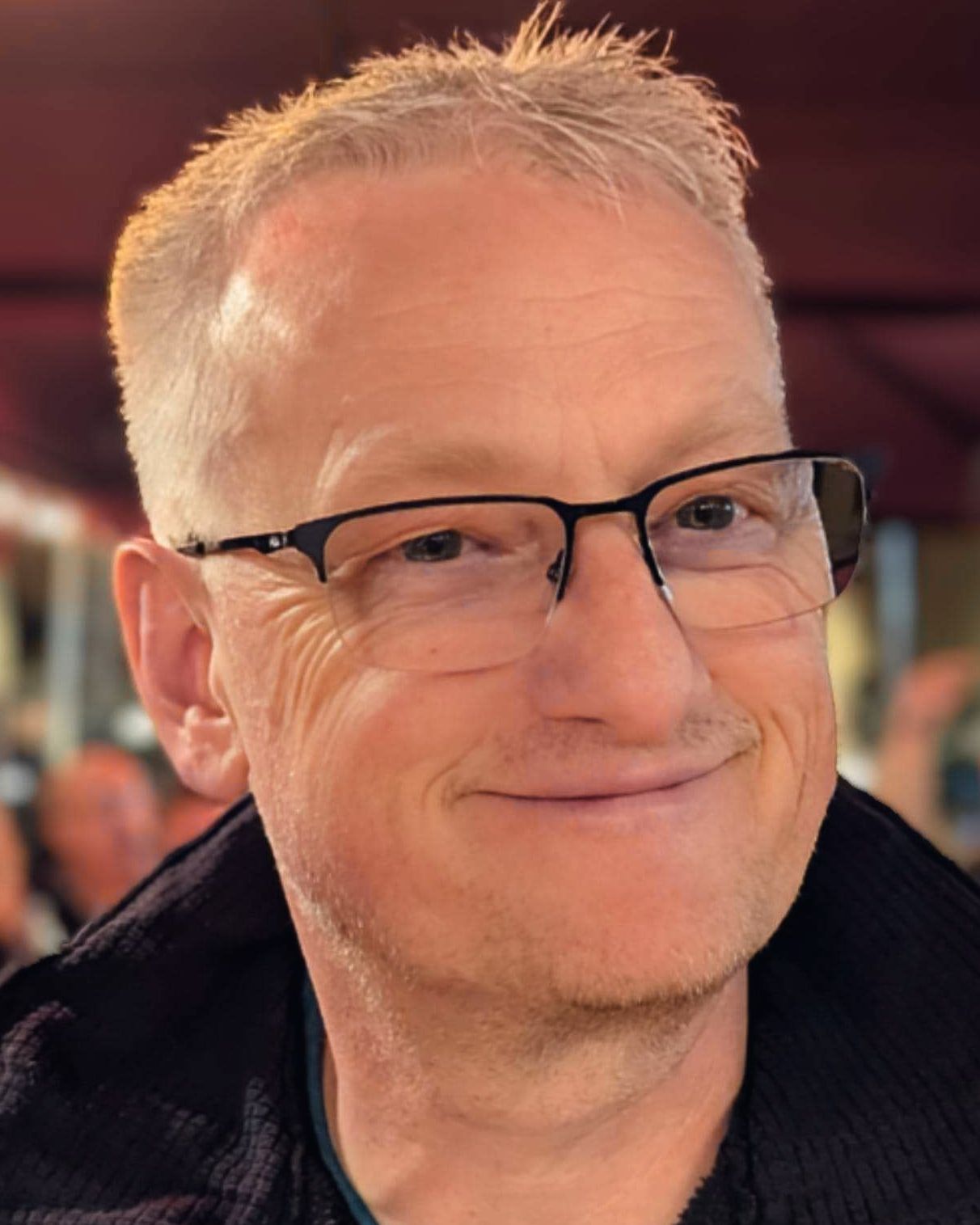 Joël Lindecker, souriant, lunettes à fine monture, en veste sombre.